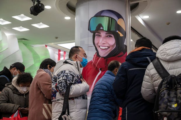 Customers crowd under a photo of  freestyle skiing gold medallist Eileen Gu at the official Beijing 2022 Winter Olympics souvenir store in Beijing. (Photo by Kevin Frayer/Getty Images)
