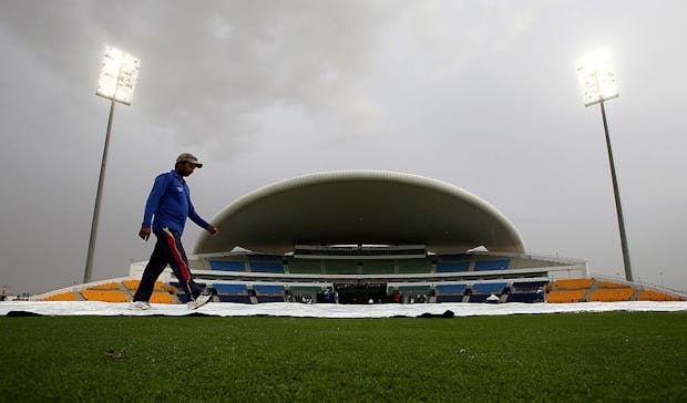 Groundsmen place covers on the wicket at Sheikh Zayed Stadium in Abu Dhabi. (Photo by Francois Nel/Getty Images)