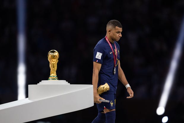 Kylian Mbappé of France walks past the World Cup trophy at Lusail Stadium on December 18, 2022 (Photo by Simon Bruty/Anychance/Getty Images)