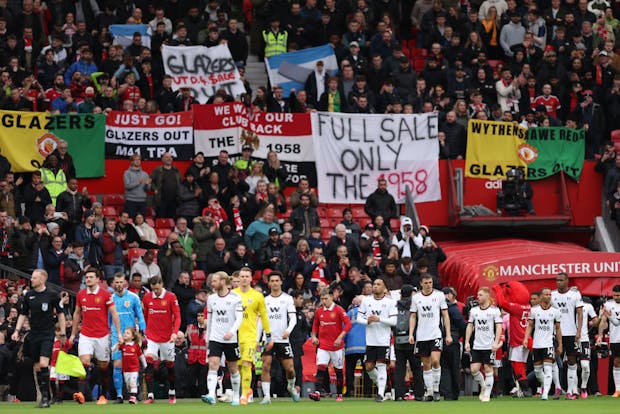 Manchester United and Fulham walk out in front of United fans protesting against the club's ownership during the FA Cup quarter final match on March 19, 2023 (by Matthew Ashton - AMA/Getty Images)