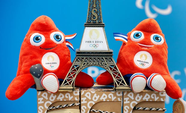 A replica of the Eiffel Tower with the logo of the 2024 Olympic Games surrounded by official Paris 2024 mascots (Photo by Chesnot/Getty Images)