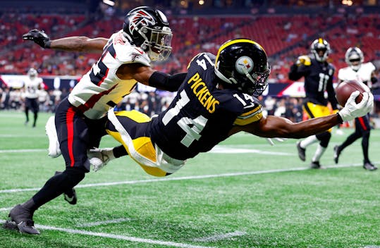 ATLANTA, GEORGIA - AUGUST 24: George Pickens #14 of the Pittsburgh Steelers leaps for a reception over Natrone Brooks #35 of the Atlanta Falcons during the first quarter of a preseason game at Mercedes-Benz Stadium on August 24, 2023 in Atlanta, Georgia. (Photo by