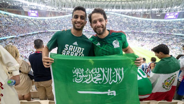 LUSAIL, QATAR - NOVEMBER 26: A Saudi Arabia and Mexico fan pose for a photograph with a Saudi Arabia flag after a FIFA World Cup Qatar 2022 Group C match between Mexico and Argentina at Lusail Stadium on November 26, 2022 in Lusail, Qatar. (Photo by