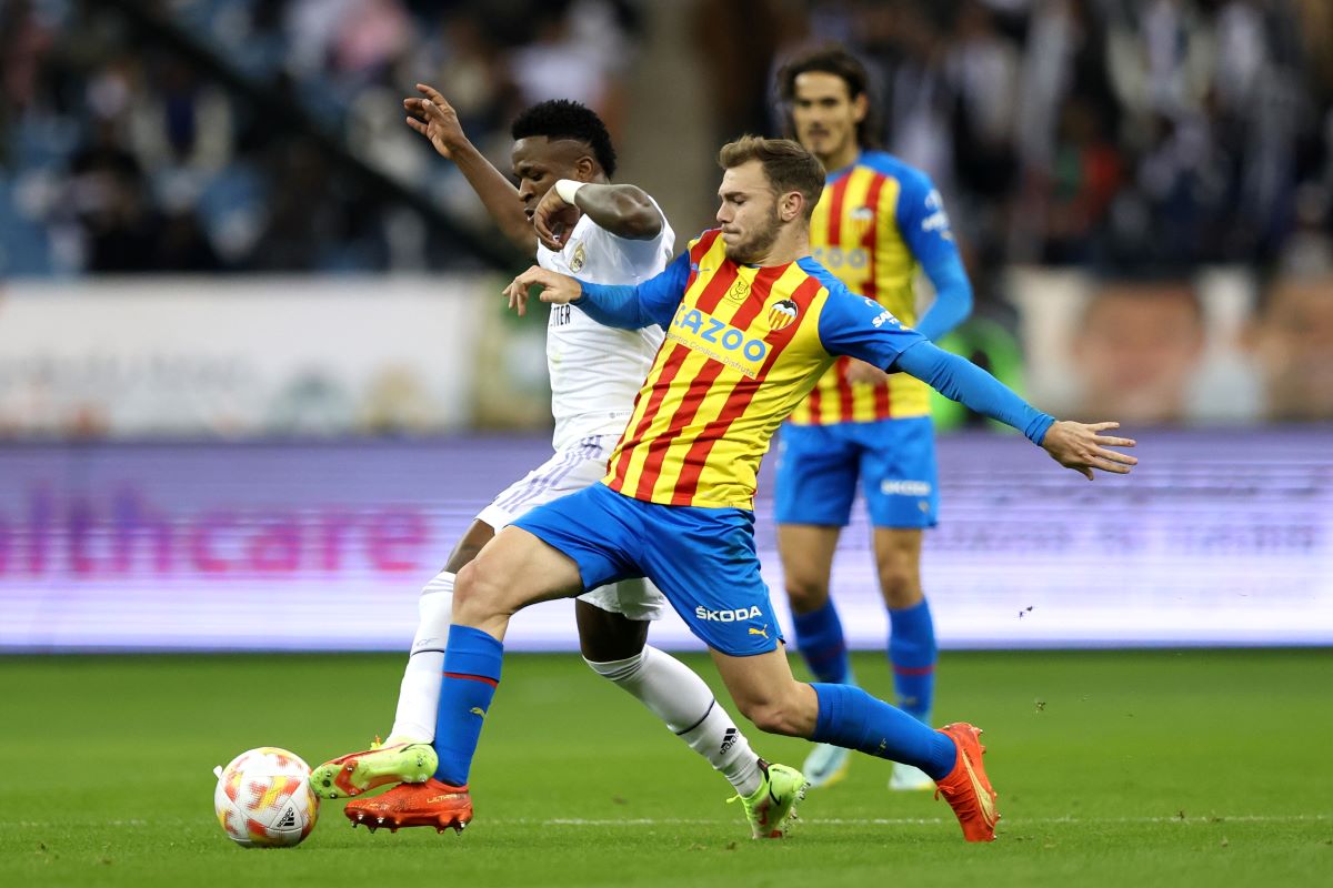RIYADH, SAUDI ARABIA - JANUARY 11: Vinicius Junior of Real Madrid is challenged by Toni Lato of Valencia CF during the Super Copa de Espana match between Real Madrid and Valencia CF at King Fahd International Stadium on January 11, 2023 in Riyadh, Saudi Arabia. (Photo by Yasser Bakhsh/Getty Images)
