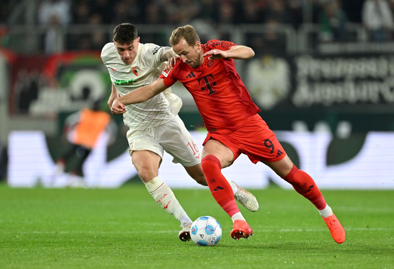 AUGSBURG, GERMANY - APRIL 04: Cedric Zesiger of FC Augsburg battles for possession with Harry Kane of Bayern Munich during the Bundesliga match between FC Augsburg and FC Bayern München at WWK-Arena on April 04, 2025 in Augsburg, Germany. (Photo by Sebastian Widmann/Getty Images)