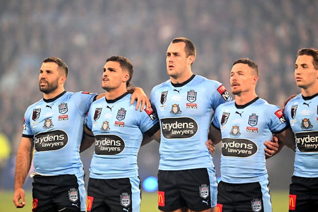NSW Blues players embrace for the national anthem before game three of the 2022 State of Origin Series (by Bradley Kanaris/Getty Images)